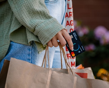 hand carrying shopping bag and a Travelex Money Card